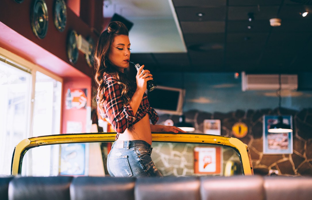 Pin up girl drinking cola in hip cafe